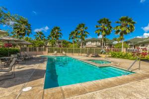 a swimming pool with tables and chairs and palm trees at Nohea Villa in Princeville