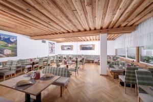 サンクト・ジョアン・イン・チロルにあるHotel Fischerの木製の天井、テーブルと椅子のあるレストラン