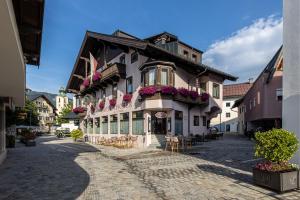 ein Gebäude in einer Straße mit Tischen und Stühlen in der Unterkunft Hotel Fischer in Sankt Johann in Tirol