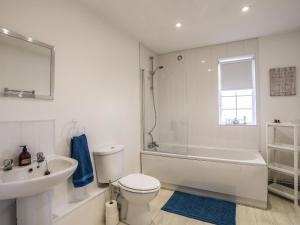 a white bathroom with a tub and a toilet and a sink at Cwt Ci in Llangefni