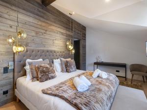sypialnia z dużym łóżkiem i drewnianą ścianą w obiekcie Chalet de charme à Courchevel, 4 chambres, sauna, cheminée, proche commerces et pistes - FR-1-562-59 w Courchevel