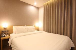 釜山にあるHotel Prima Busanの白い大型ベッド1台と窓が備わるホテルルームです。