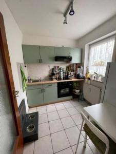 cocina con armarios verdes y suelo de baldosa blanca en Complete Apartment peacefully situated near the Airport Nürnberg, en Núremberg