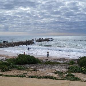 un groupe de personnes jouant dans l'eau à la plage dans l'établissement Nandos Apartement, à Costa da Caparica