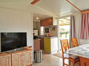 een keuken met een grote televisie en een tafel met stoelen bij L Escale - 6 personnes in Saint-Hilaire-de-Talmont