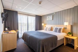 Cette chambre comprend un grand lit et une fenêtre. dans l'établissement Hotel De Boei, à Egmond aan Zee