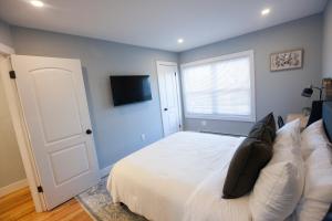 a bedroom with a white bed and a window at Alafia- Cozy JFK Area Home - This property is a hosted property meaning the host live on site in Locust Manor