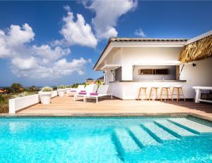 a villa with a swimming pool and a house at Coral Estate Rentals in Willibrordus