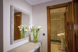 a bathroom with a mirror and a vase with white flowers at Hotel Bajamar Centro in Nerja