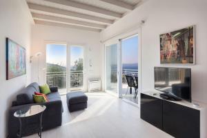 a living room with a couch and a television and a balcony at Villa Malù - APT Luisa Piscina e vista lago in Torri del Benaco