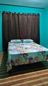 una cama con un edredón de flores encima en Alba House, en Puerto Jiménez