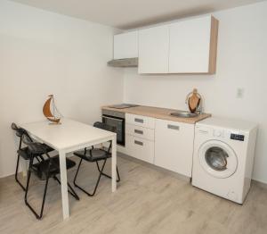 a kitchen with a table and a washing machine at Ricky Apartments in Novalja