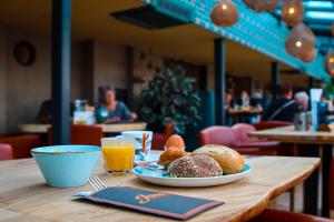 una mesa con un plato de bollería y zumo de naranja en Hotel De Boei en Egmond aan Zee