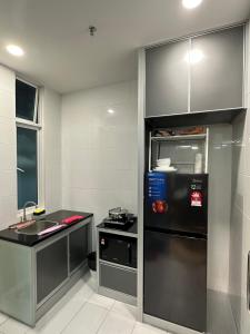a kitchen with a black refrigerator and a sink at Melaka Duplex Penthouse 3 Bedroom The Wave Residence 9pax in Melaka