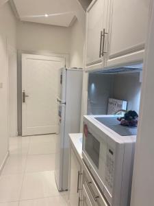 a kitchen with white cabinets and a white refrigerator at MED Luxury Suites and Apparts in Al Madinah