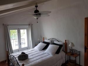 ein Schlafzimmer mit einem weißen Bett mit Deckenventilator in der Unterkunft Maison Andalouse avec piscine in El Almendral