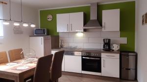 a kitchen with white cabinets and a table with chairs at Ferienwohnung Reißmann in Heinsdorfergrund