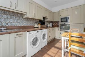 cocina con armarios blancos, lavadora y secadora en Stylish country home near East Linton and Edinburgh, en Whittingehame