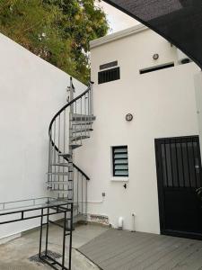 een wit gebouw met een trap naast een deur bij L’aire sans soucis in Le Bois de Nèfles