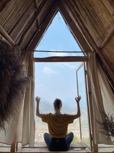 a person sitting on a window sill looking out at Imani Eco Sky Lodge Ngoc Chien in Nam San