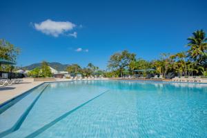 a large swimming pool with chairs and palm trees at Xeliter Green One Playa Dorada in San Felipe de Puerto Plata