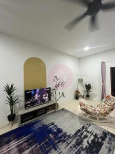 a living room with a flat screen tv and a chair at AfiRA Homestay Cherating in Kuantan
