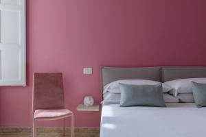 - une chambre avec un mur rose, un lit et une chaise dans l'établissement Il Sovrano, à Catane