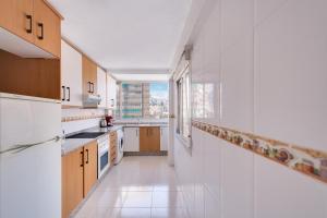 ベニドルムにあるLevante Sunset Front line apartment Almadrabaの白い家電製品付きのキッチン、大きな窓