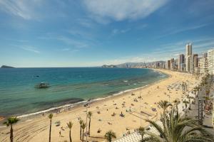 a beach with a lot of people and the ocean at Levante Sunset Front line apartment Almadraba in Benidorm