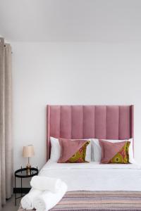 a bedroom with a large bed with a purple headboard at Rest on Millvale guest house in Cape Town