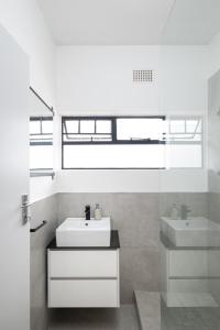 a white bathroom with a sink and a mirror at Rest on Millvale guest house in Cape Town