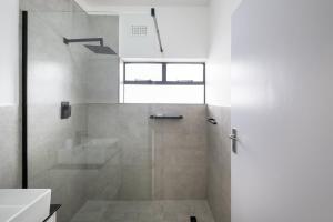 a bathroom with a shower with a glass door at Rest on Millvale guest house in Cape Town
