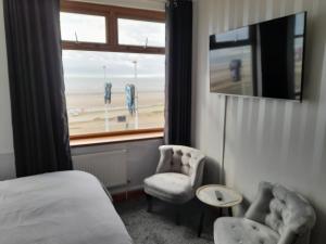 um quarto com uma cama, 2 cadeiras e uma janela em The Fame em Blackpool