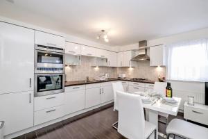 een keuken met witte kasten en een tafel met witte stoelen bij Orange Apartments - Kepplestone in Aberdeen