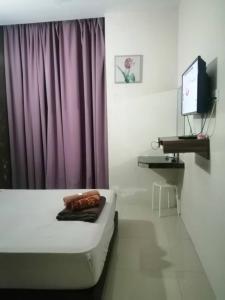 een kamer met een bed, een tv en een paars gordijn bij TGL Aparthotel Tanjung Lumpur in Kuantan