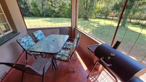 un porche cubierto con mesa y sillas en Pine Forest Cottage en Sabie