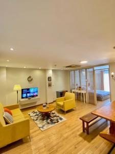 a living room with yellow furniture and a flat screen tv at The Palmian City Center Serviced Apartment in Ho Chi Minh City