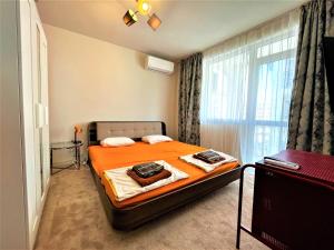 a bedroom with a bed with orange sheets and a window at Bravo 5 Holiday Home in Sunny Beach