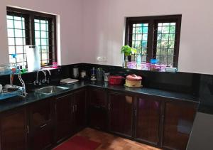 una cocina con encimeras negras, fregadero y ventanas en Karapuzha Homestay, en Meenangadi