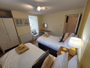 a room with two beds and a table with a lamp at Llys Bach Apartment at Llys Aeron in Aberaeron