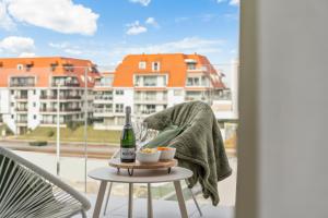 a person sitting on a chair on a balcony with a bottle of wine at Orion View - brand new apartment with swimming pool in Nieuwpoort