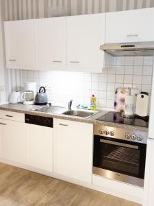 a kitchen with white cabinets and a sink at Tauchparadies Kreidesee in Hemmoor