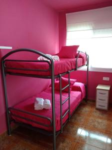 um quarto com 2 beliches e paredes cor-de-rosa em El raconet del Riu em Deltebre
