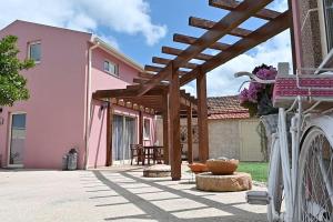 a patio with a wooden pergola next to a pink house at Casinhas Escondidinho 