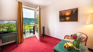 sala de estar con TV y mesa con fruta. en Hotel Drachenwand-Mondsee, en Mondsee