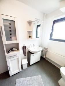 a white bathroom with a sink and a toilet at Tauchparadies Kreidesee in Hemmoor