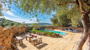 un patio al aire libre con mesa y piscina en Casa de Piedra La Laguna de Tiscar Puente Genil by Ruralidays en Puente-Genil