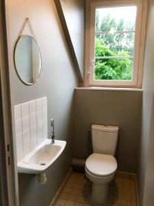 La salle de bains est pourvue de toilettes, d'un lavabo et d'une fenêtre. dans l'établissement Villa Marie-Lou entièrement rénovée, à Neuville-sous-Montreuil