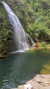 una cascada y un estanque frente a un cuerpo de agua en Chalé Cipó Maia en Serra do Cipo