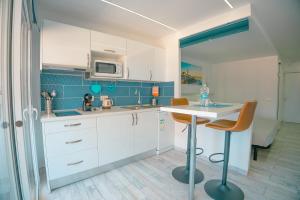 a kitchen with white cabinets and a table and chairs at Piso Paraíso vicino al mare in Maspalomas
